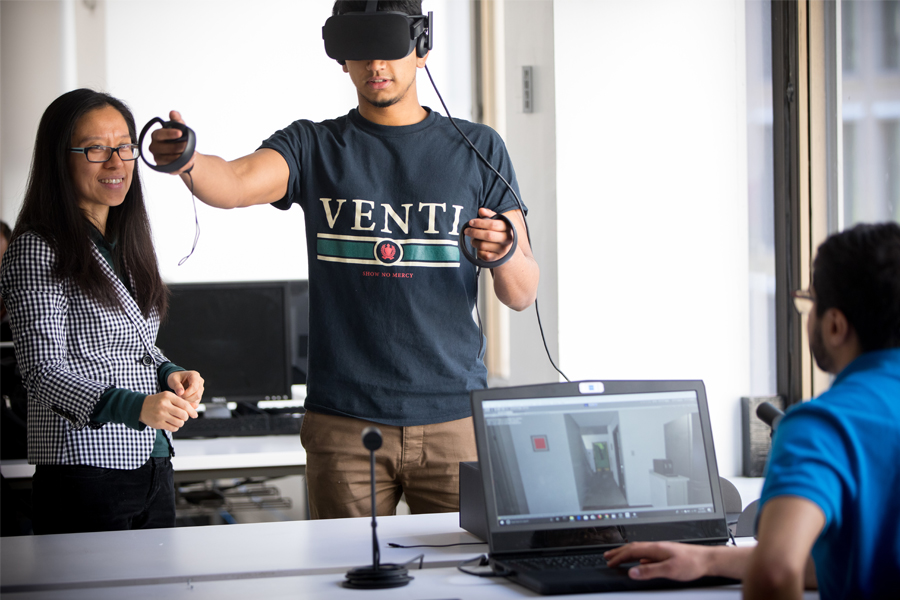 Student with VR set working with two other students.