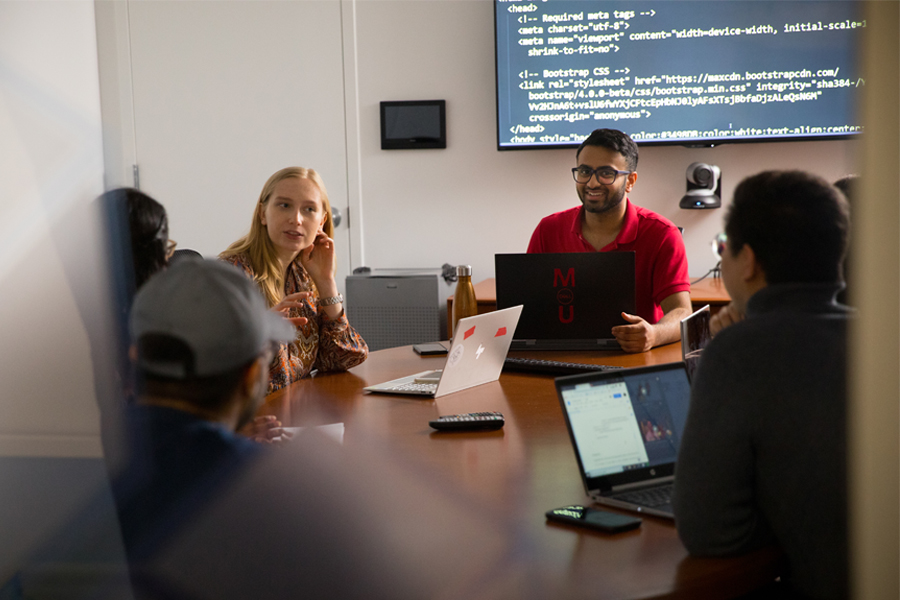 Group of students in a meeting room with laptops.