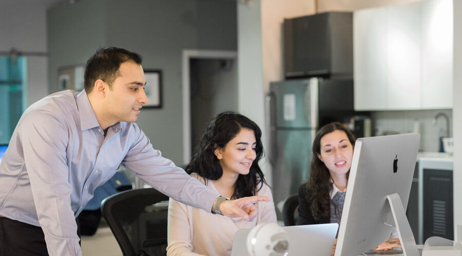 A group of three students review information on a computer.