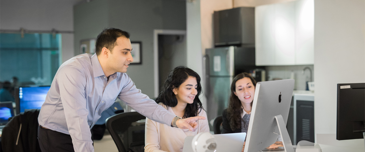 A group of three students review information on a computer.