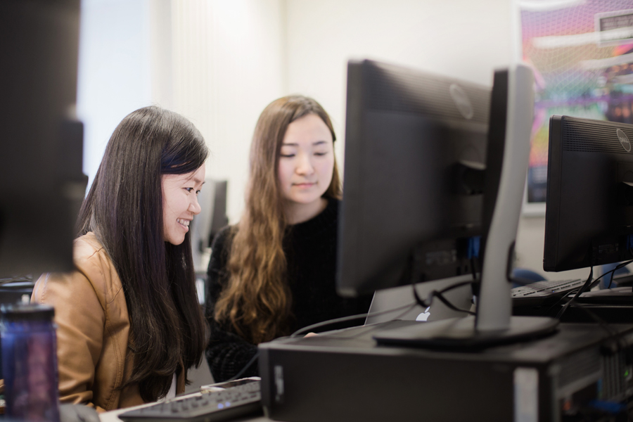 Two students review information at a computer.