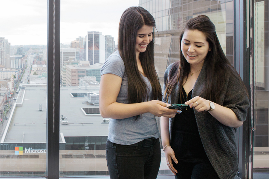 Two students chat about something on their phones.