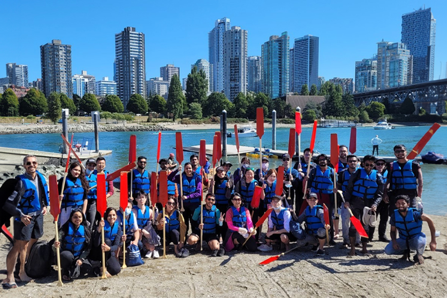 New York Tech Vancouver students pose by a river with oars before embarking on a canoeing trip.