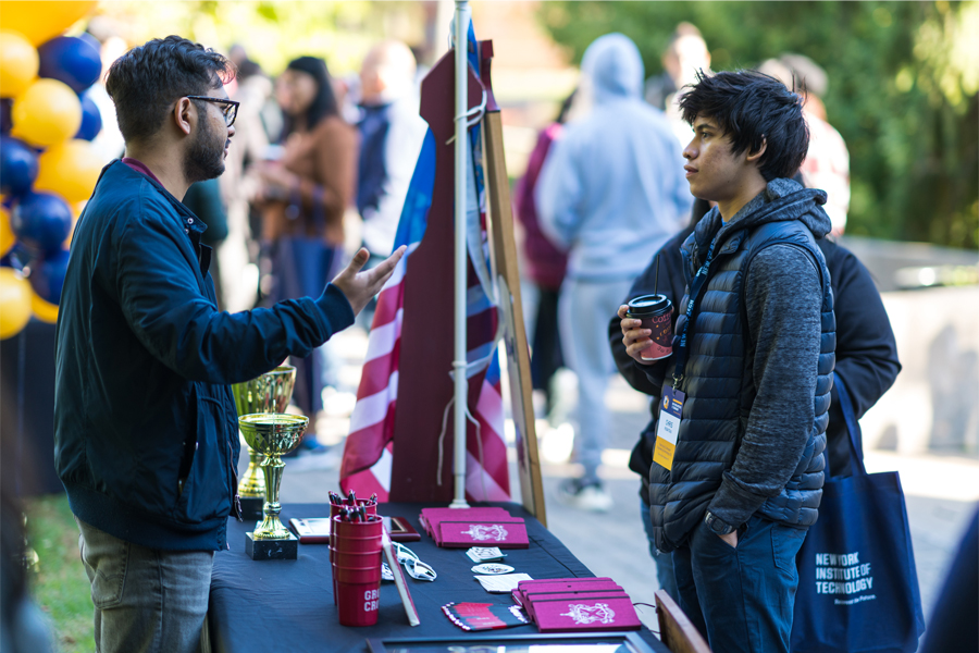 Two students talk during a club and student organization fair held outside New York Tech's Vancouver Campus.