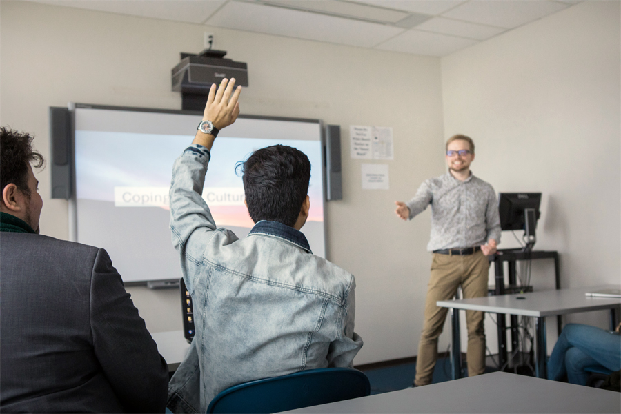 A student raises their hand during a presentation in a classroom at New York Tech's Vancouver Campus.